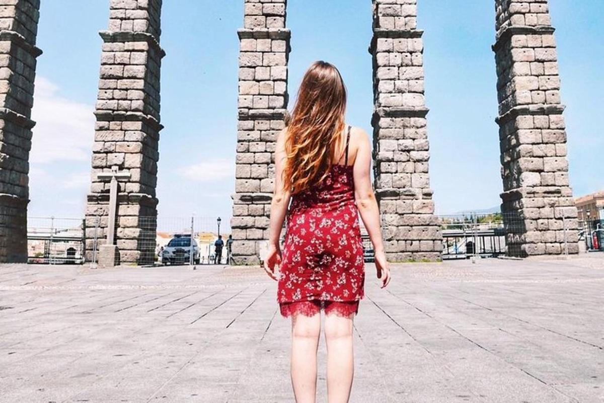 Una mujer con un vestido rojo parada frente a unas columnas.