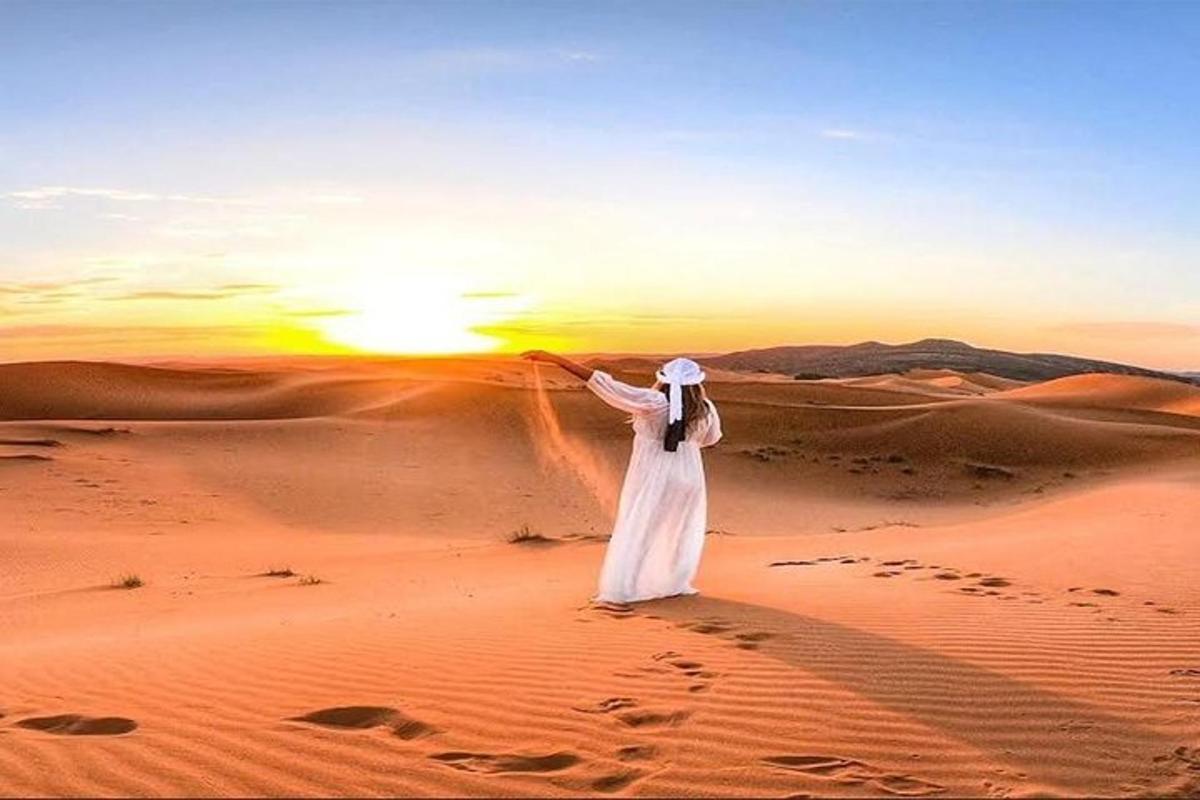 a woman standing in the desert at sunset