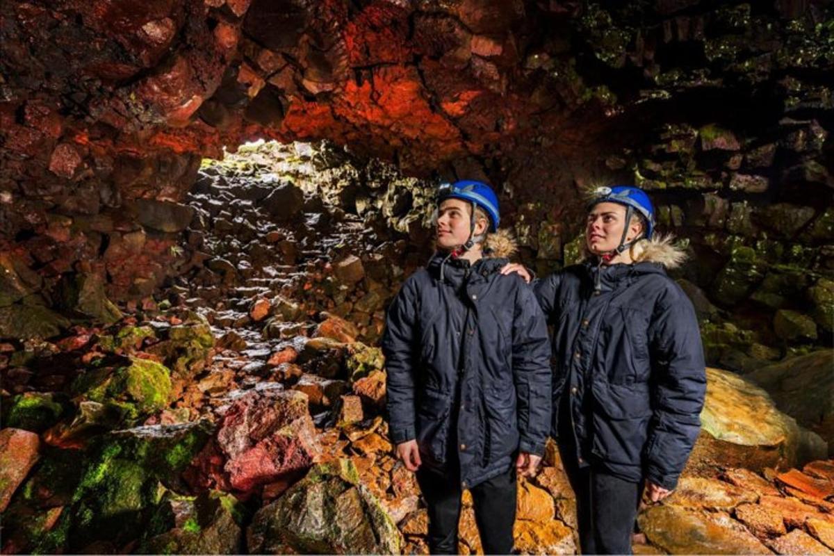 two young men standing in front of a cave