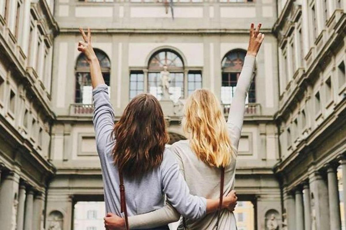 twee vrouwen staan voor een gebouw met hun handen in de lucht