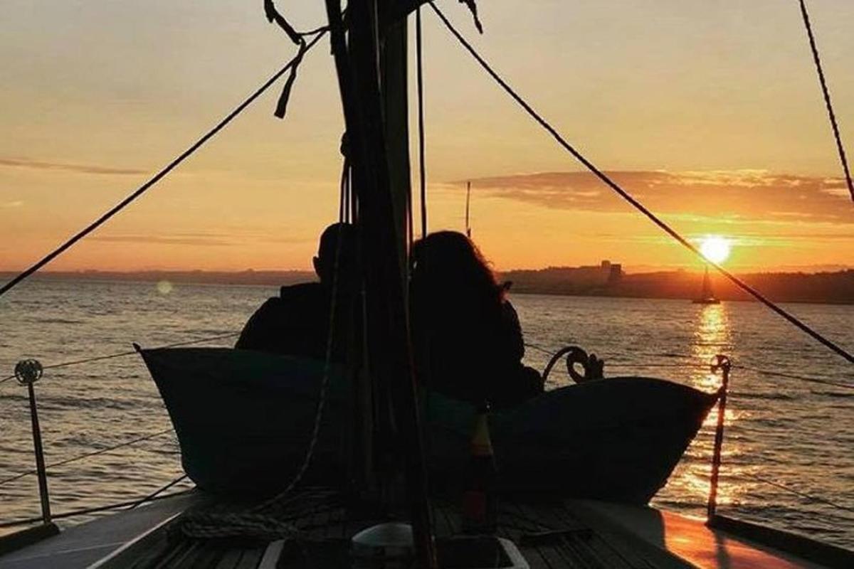 a group of people sitting on a boat at sunset