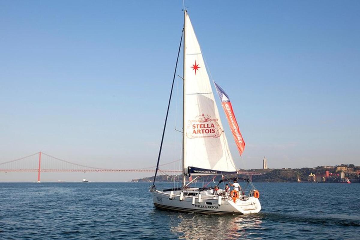 a sail boat in the water with a bridge in the background