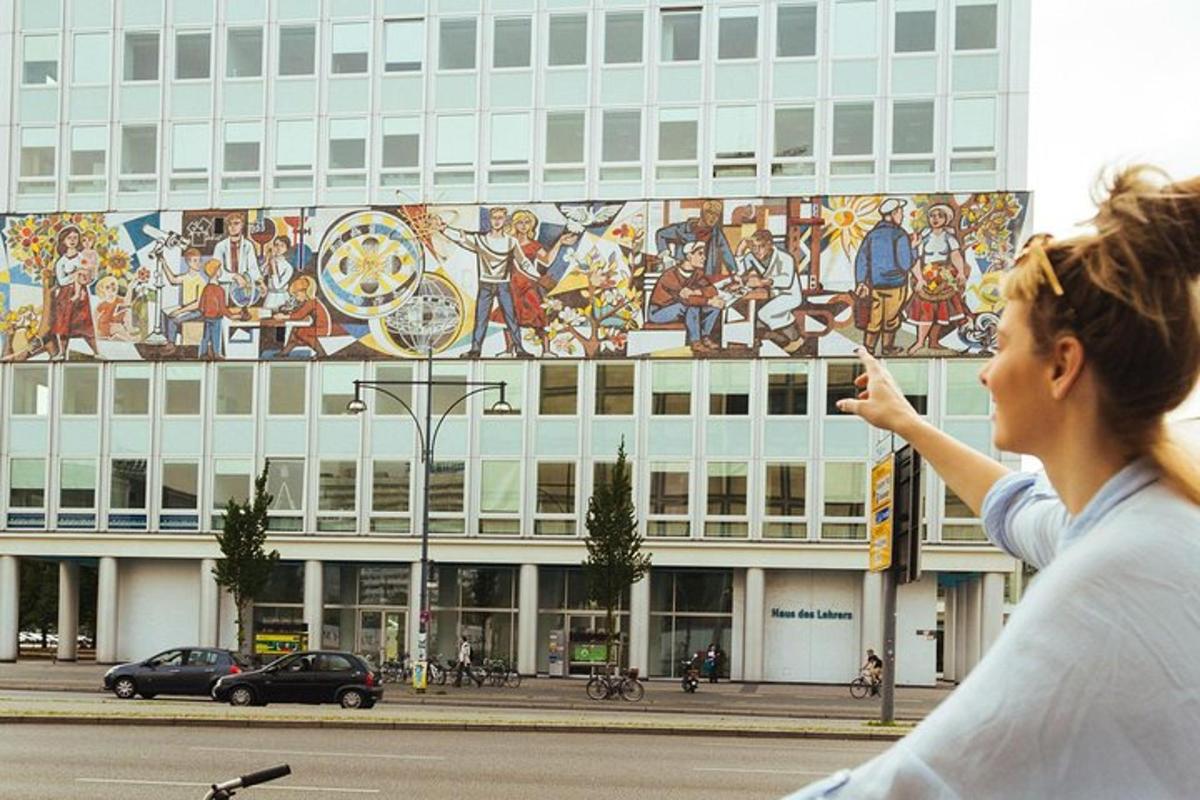 seorang wanita berdiri di hadapan sebuah bangunan dengan mural