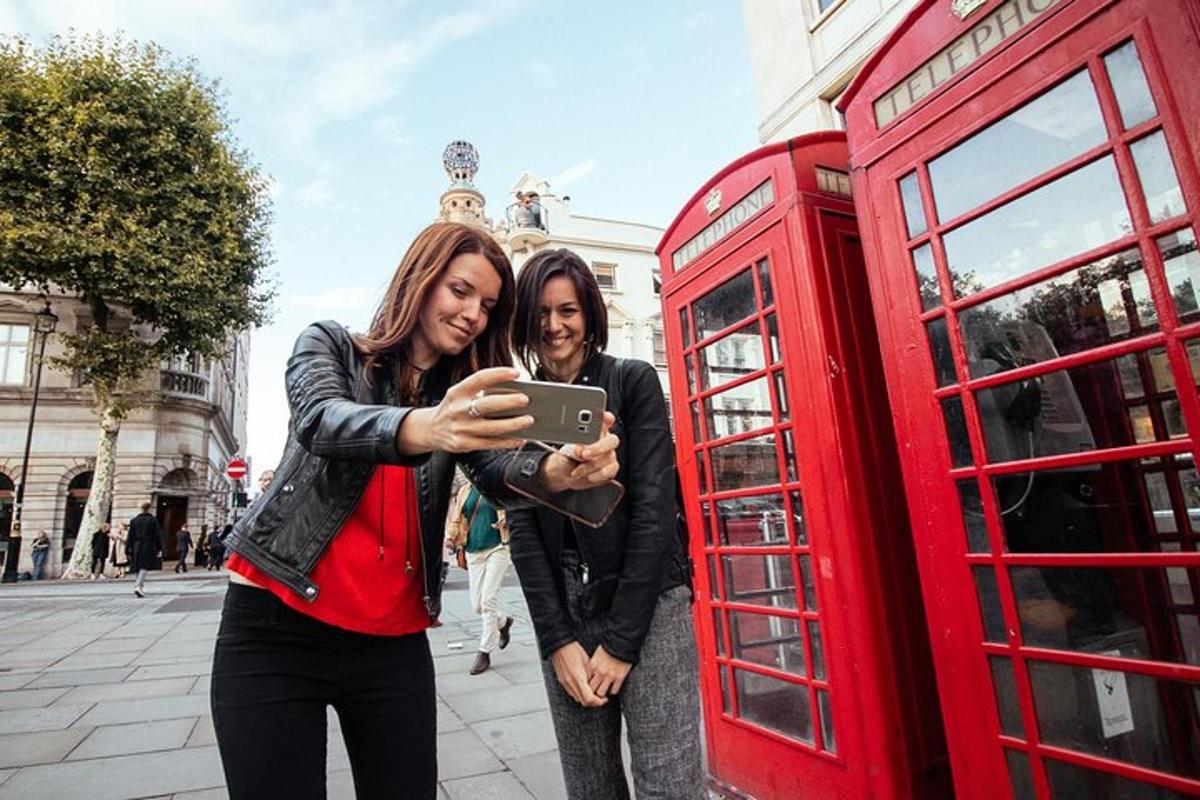 dvě ženy stojící vedle červené telefonní budky