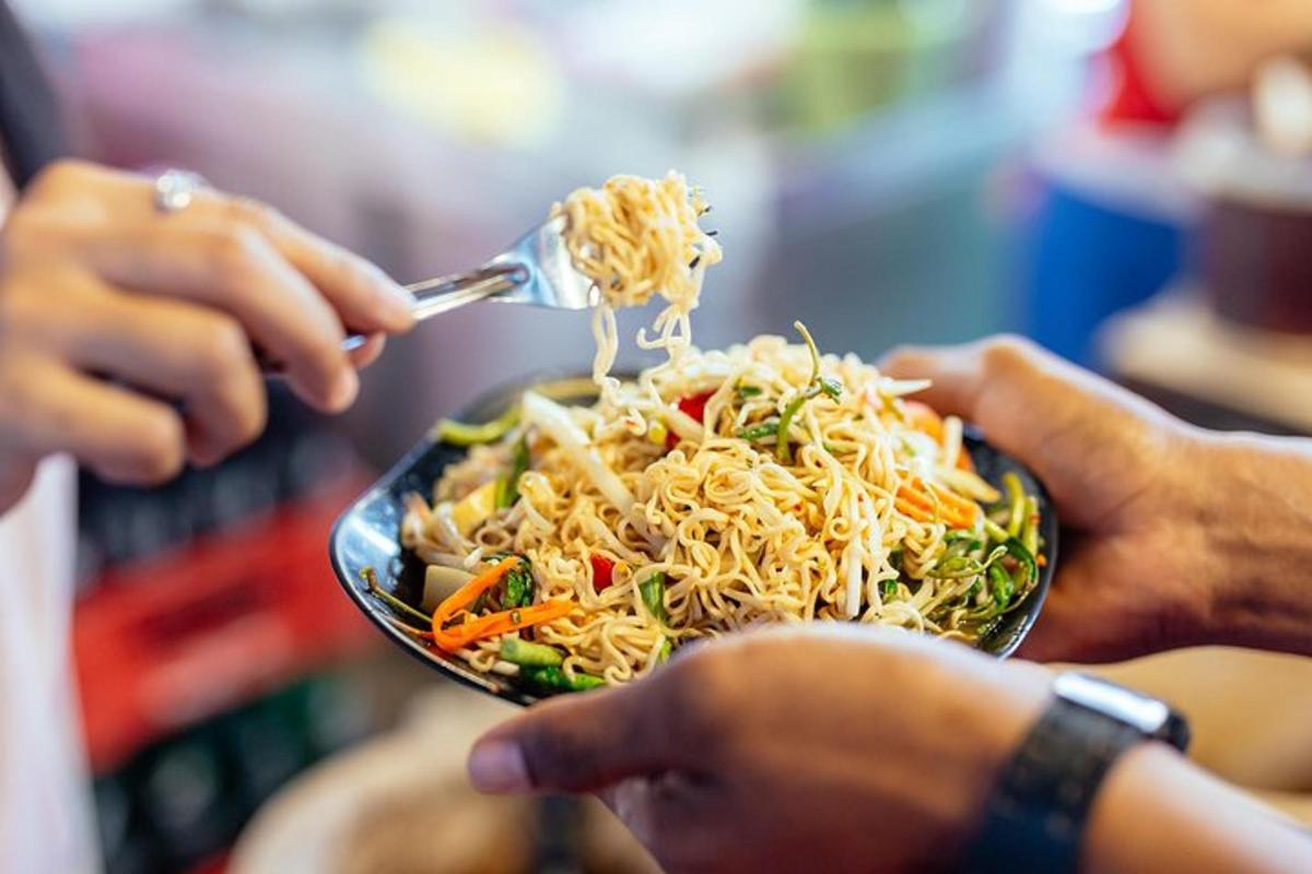 seseorang yang makan semangkuk mi dan sayur-sayuran