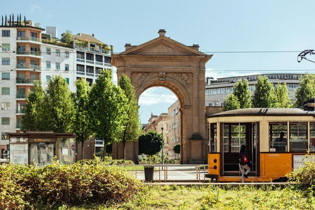 eine Straßenbahn vor einem Bogen in einer Stadt