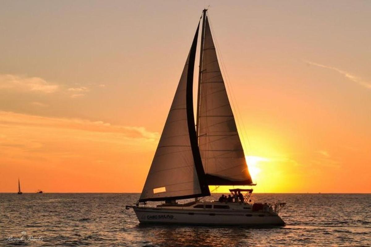 a sail boat in the ocean at sunset