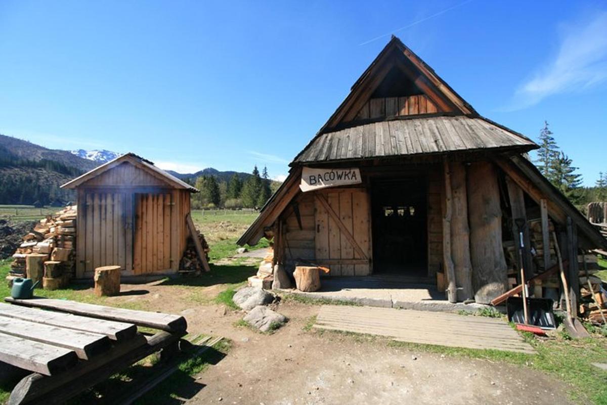 two wooden huts in a field with a picnic table