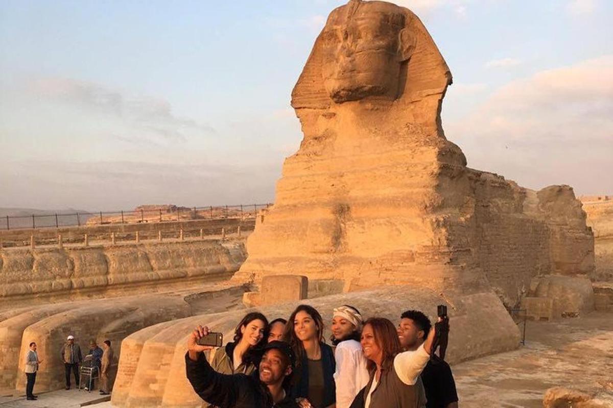 cilvēku grupa, kas stāv statujas priekšā
