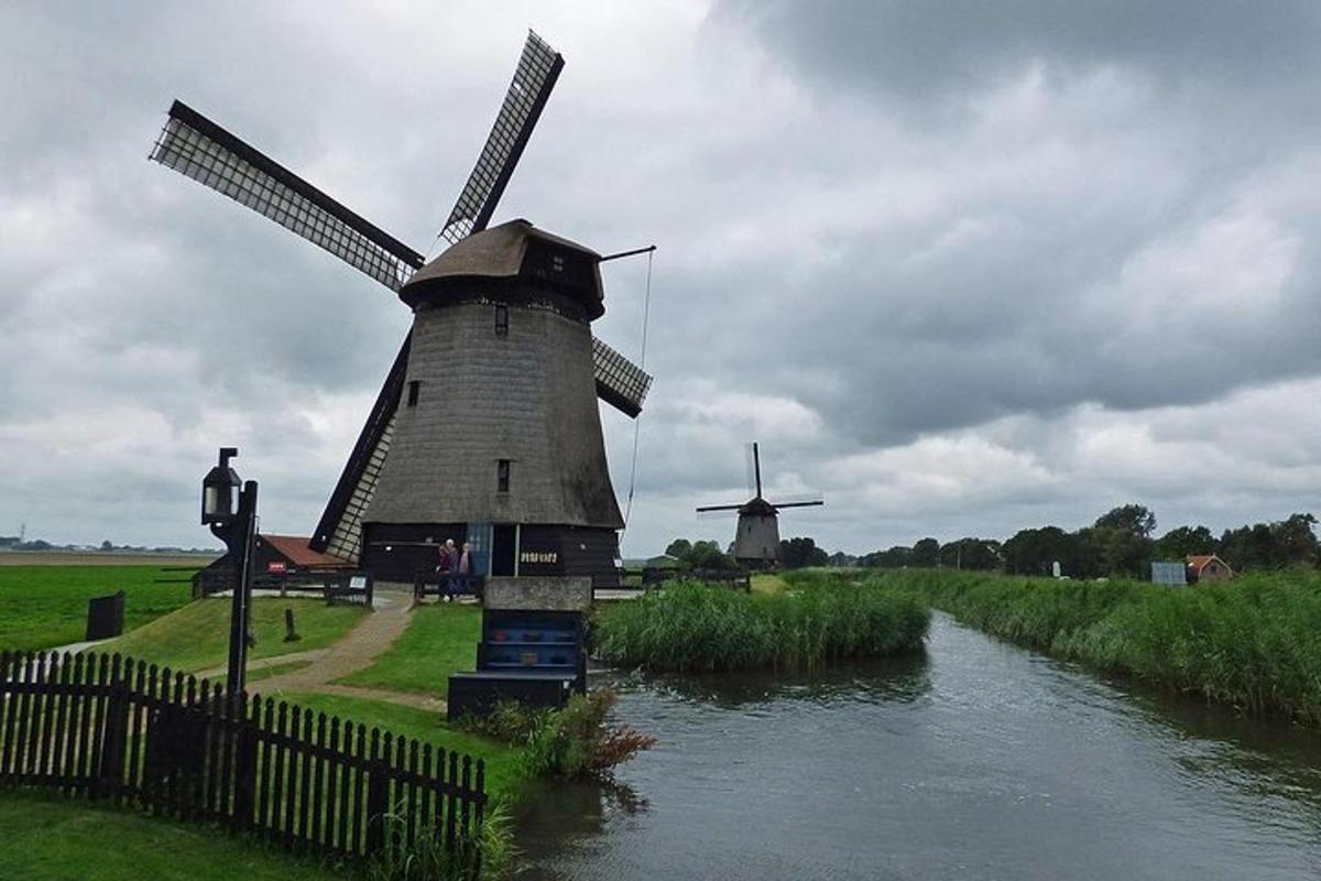 un molino de viento en un campo junto a un río