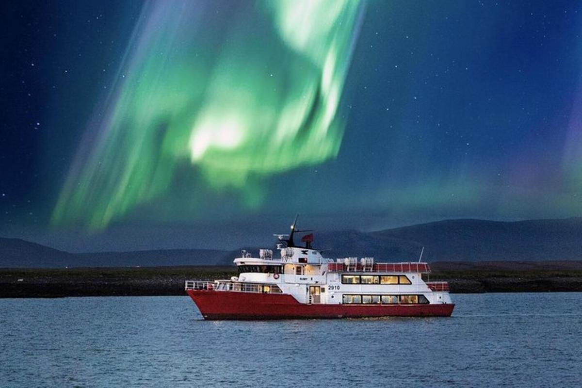 una barca rossa e bianca nell'acqua sotto l'aurora boreale