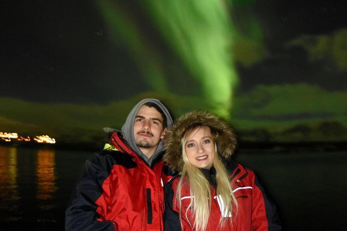 en mann og en kvinne som står foran nordlyset