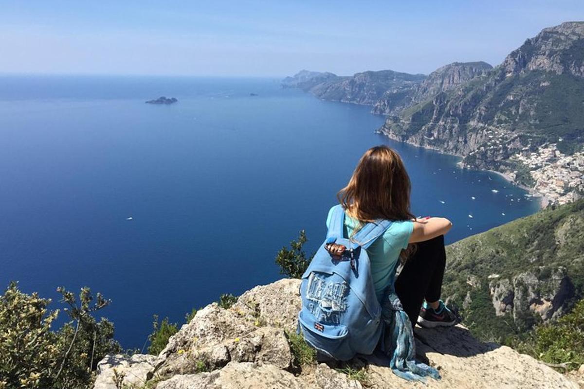 una dona asseguda al cim d'una muntanya mirant l'aigua