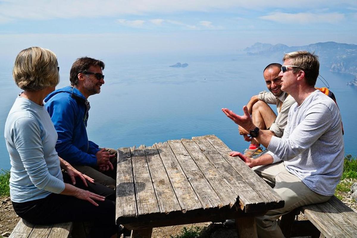 un grup de persones assegudes al voltant d'una taula de pícnic amb vistes a l'aigua