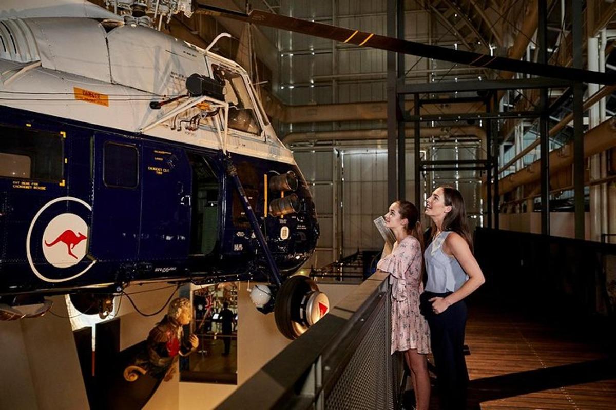 two women standing in a museum looking at a helicopter
