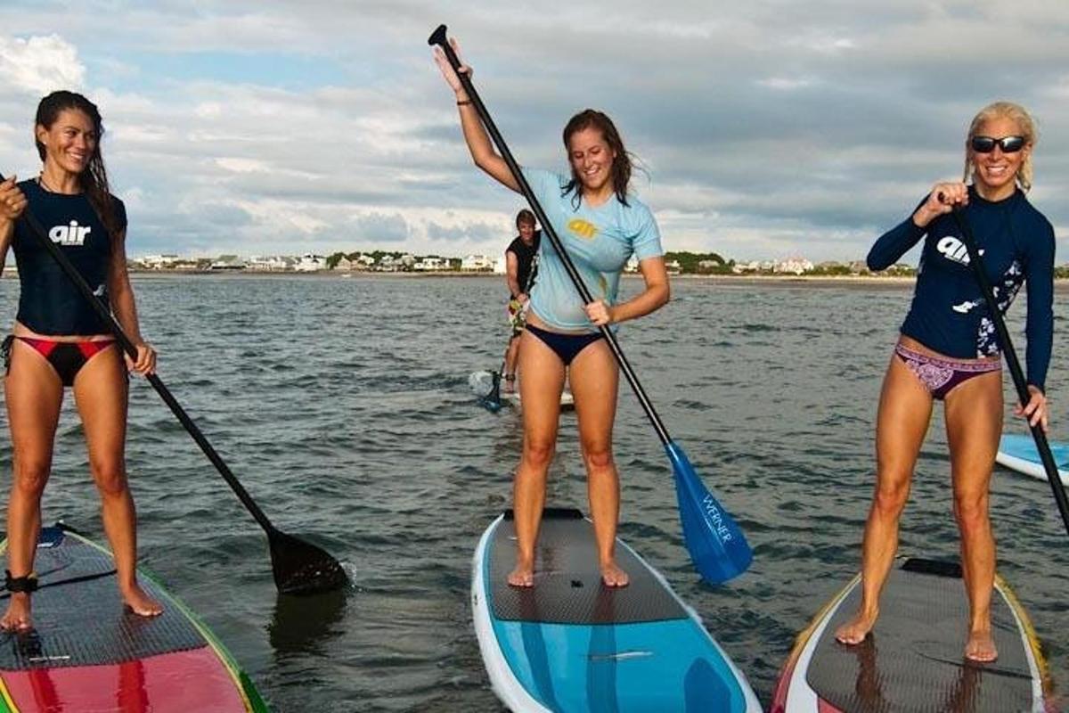 Tres chicas están de pie sobre tablas de paddle en el agua