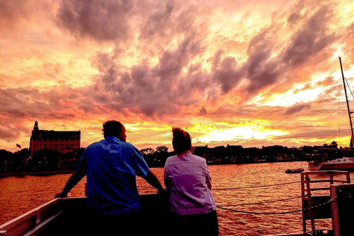 un uomo e una donna seduti su una barca che guardano il tramonto