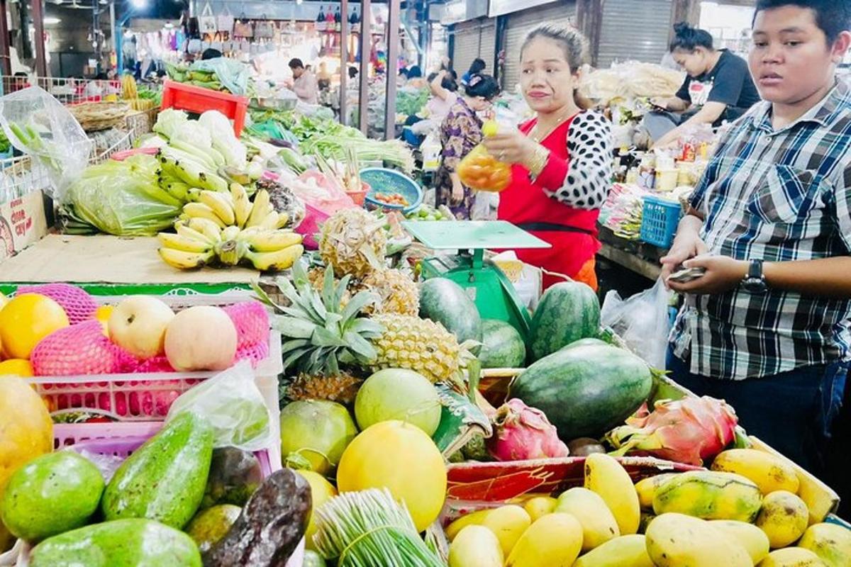 Un hombre y una mujer de pie en un mercado con frutas y verduras.