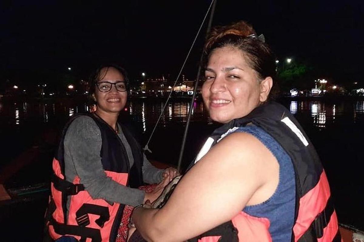 duas mulheres estão em pé em um barco na água