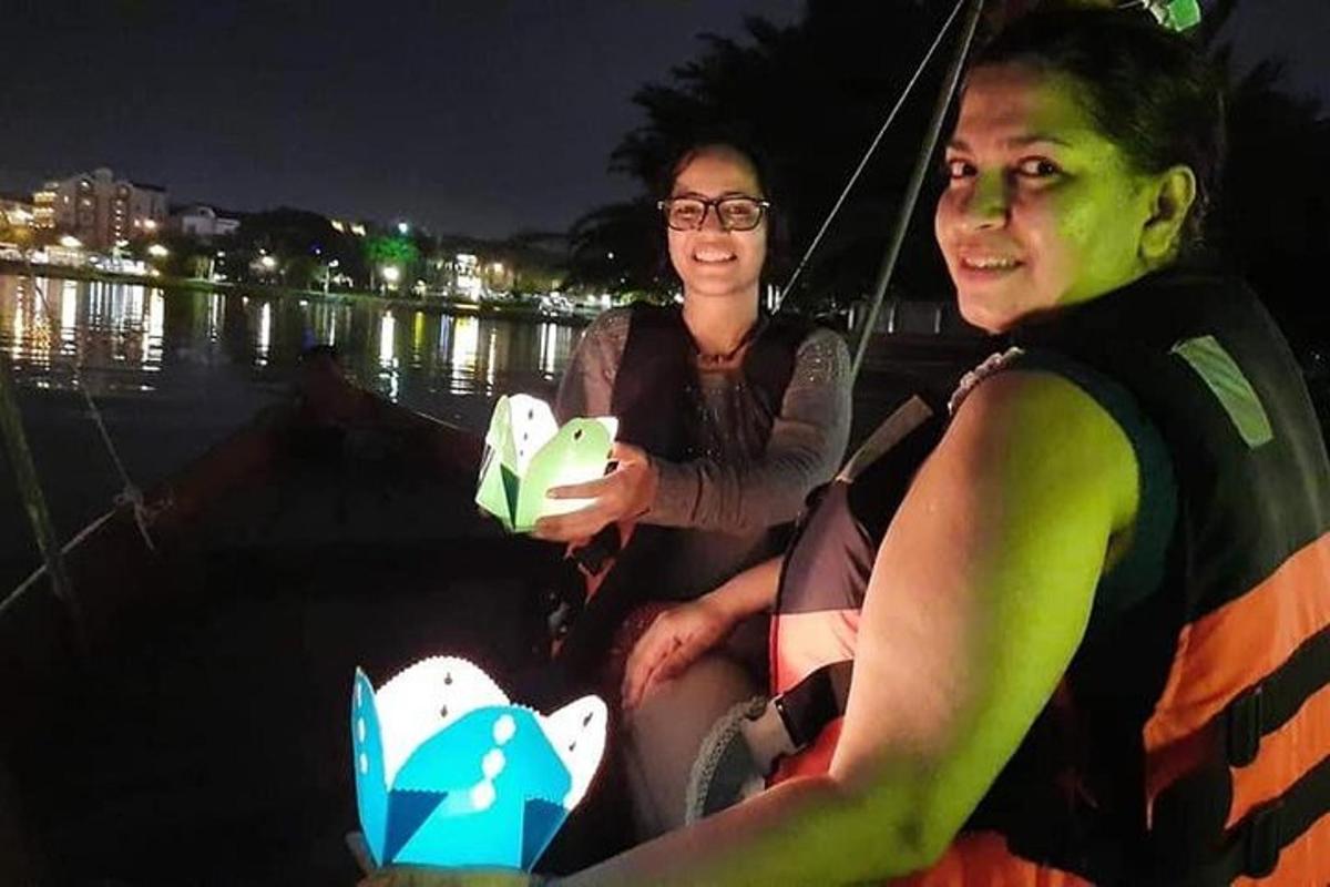 duas mulheres sentadas em um barco na água à noite