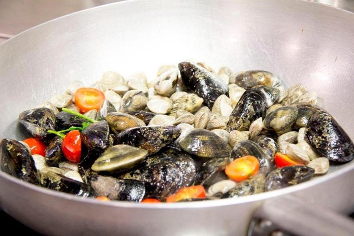 Una olla llena de mejillones y verduras en una estufa
