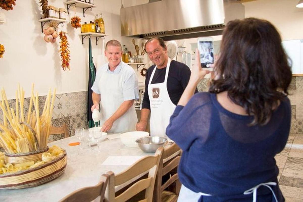 una donna che scatta una foto a due chef in cucina