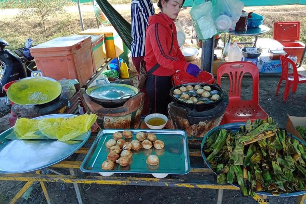 seorang wanita berdiri di sebelah meja dengan makanan di atasnya