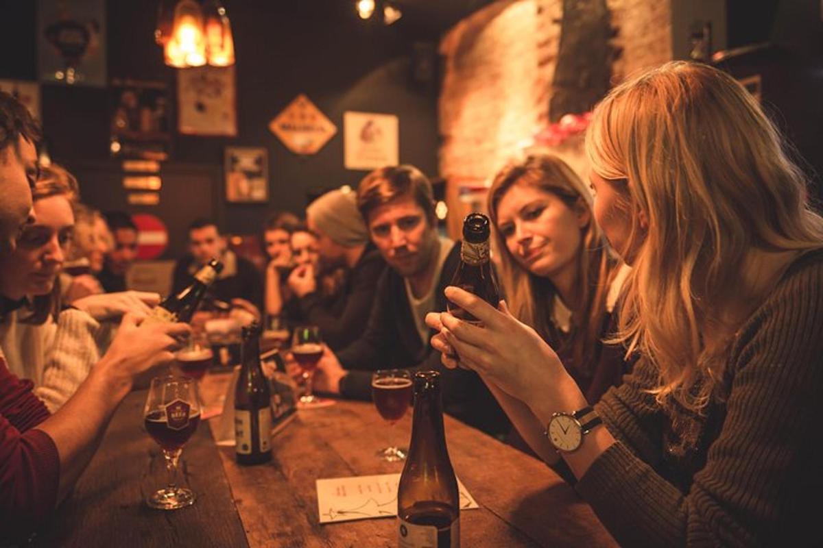a group of people sitting at a bar with bottles of wine