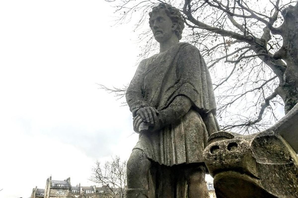 una estàtua d'una dona asseguda sobre una estàtua d'ocell