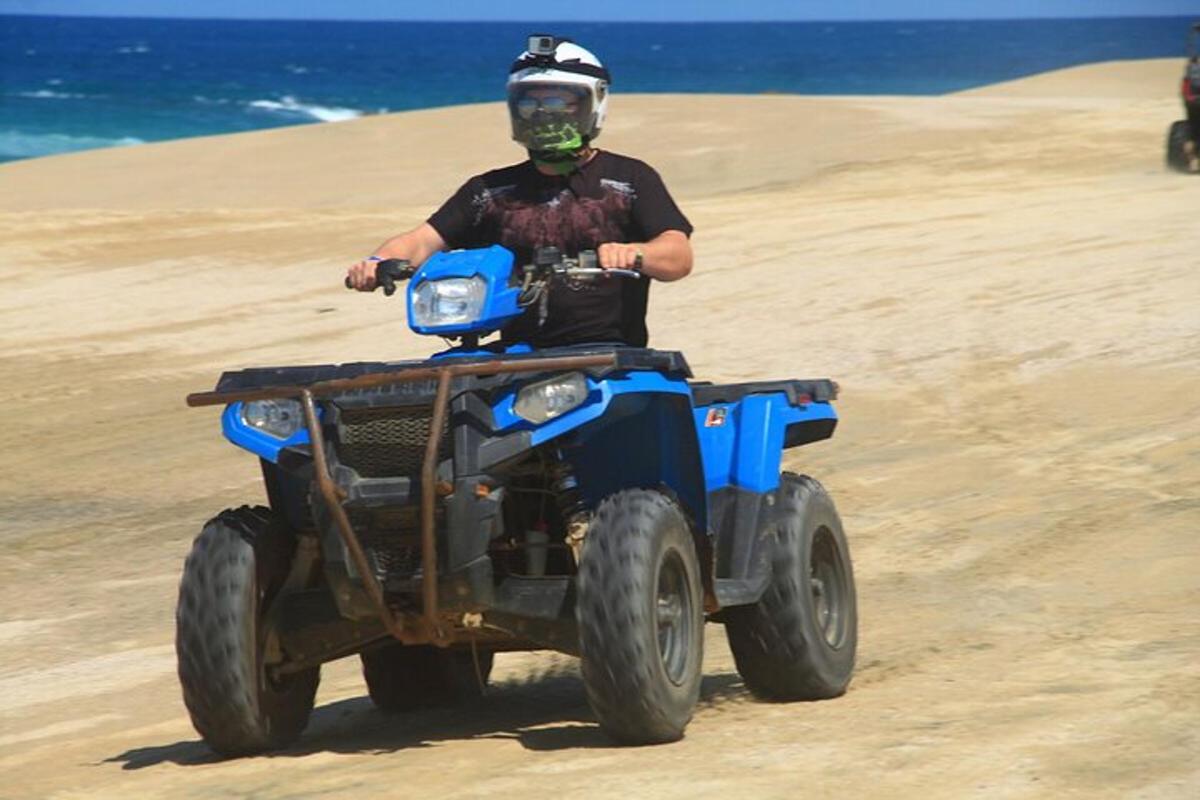 moški, ki vozi štirikolesnik na plaži