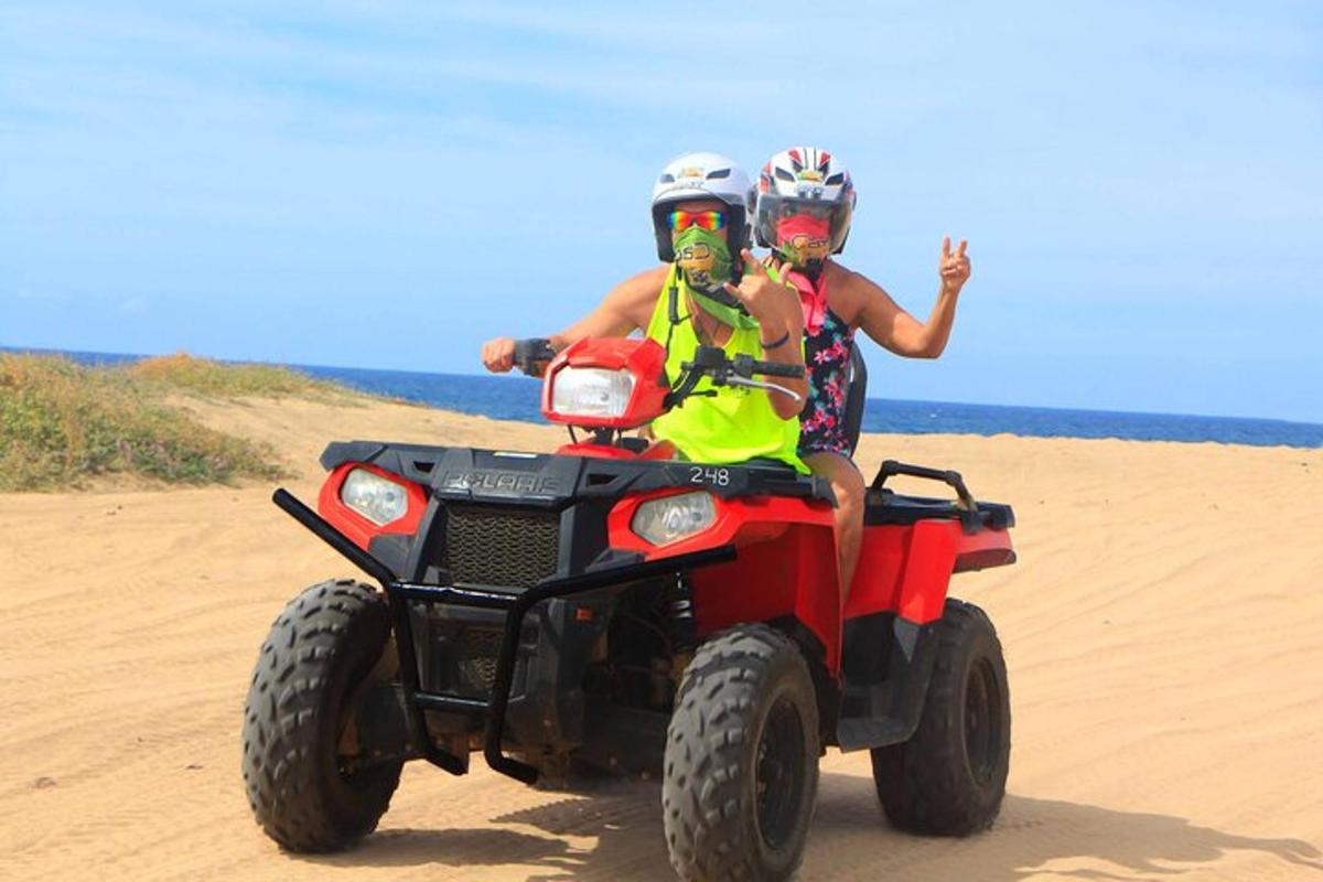dve osebi, ki se vozita na štirikolesniku na plaži