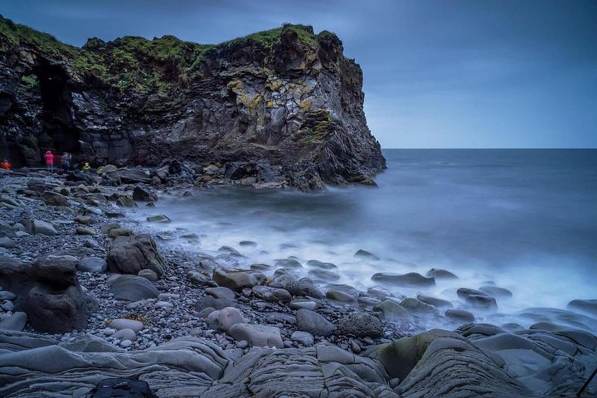 a rocky beach with the ocean and a cliff