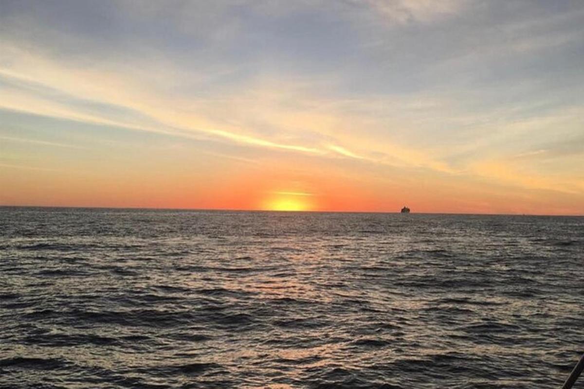 un tramonto sull'oceano con una nave in lontananza