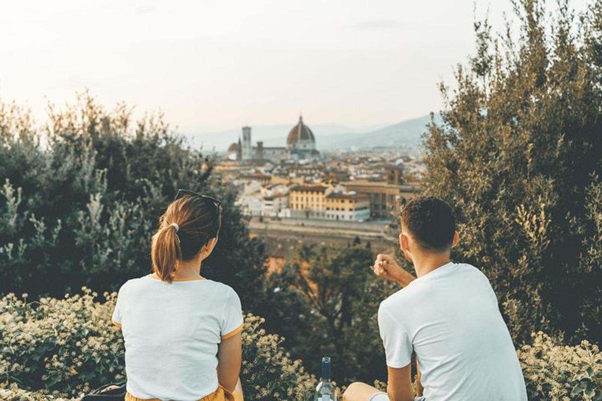 two people sitting on a hill looking at a city