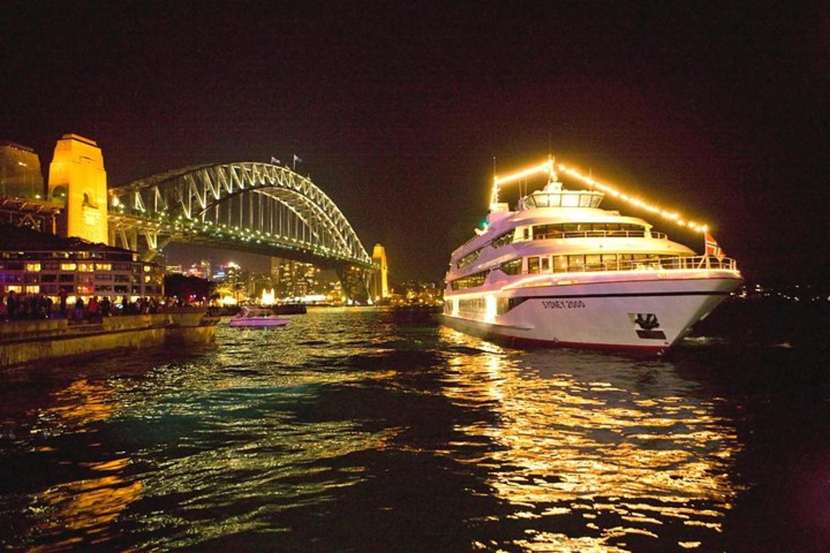 a cruise ship in the water at night with a bridge