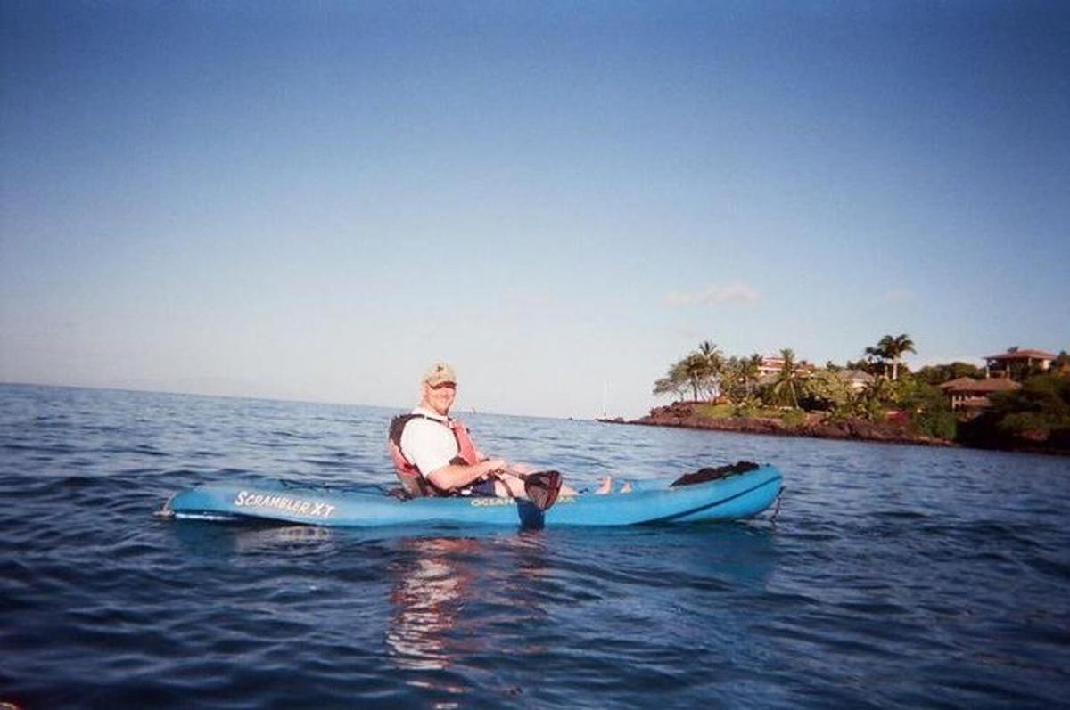 muž sedící na paddleboardu ve vodě