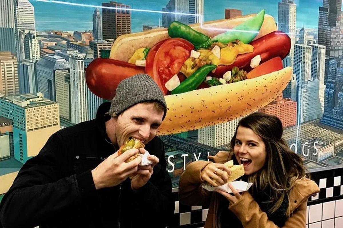 a man and a woman eating a hot dog in front of a mural