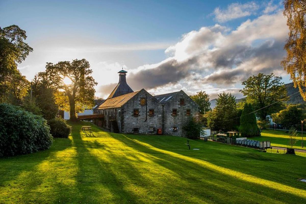 an old stone building with a tower on a green field