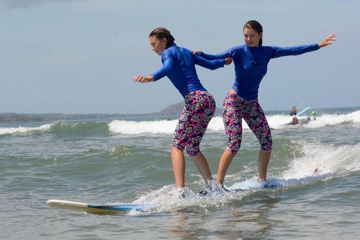 to jenter står på surfebrett i havet