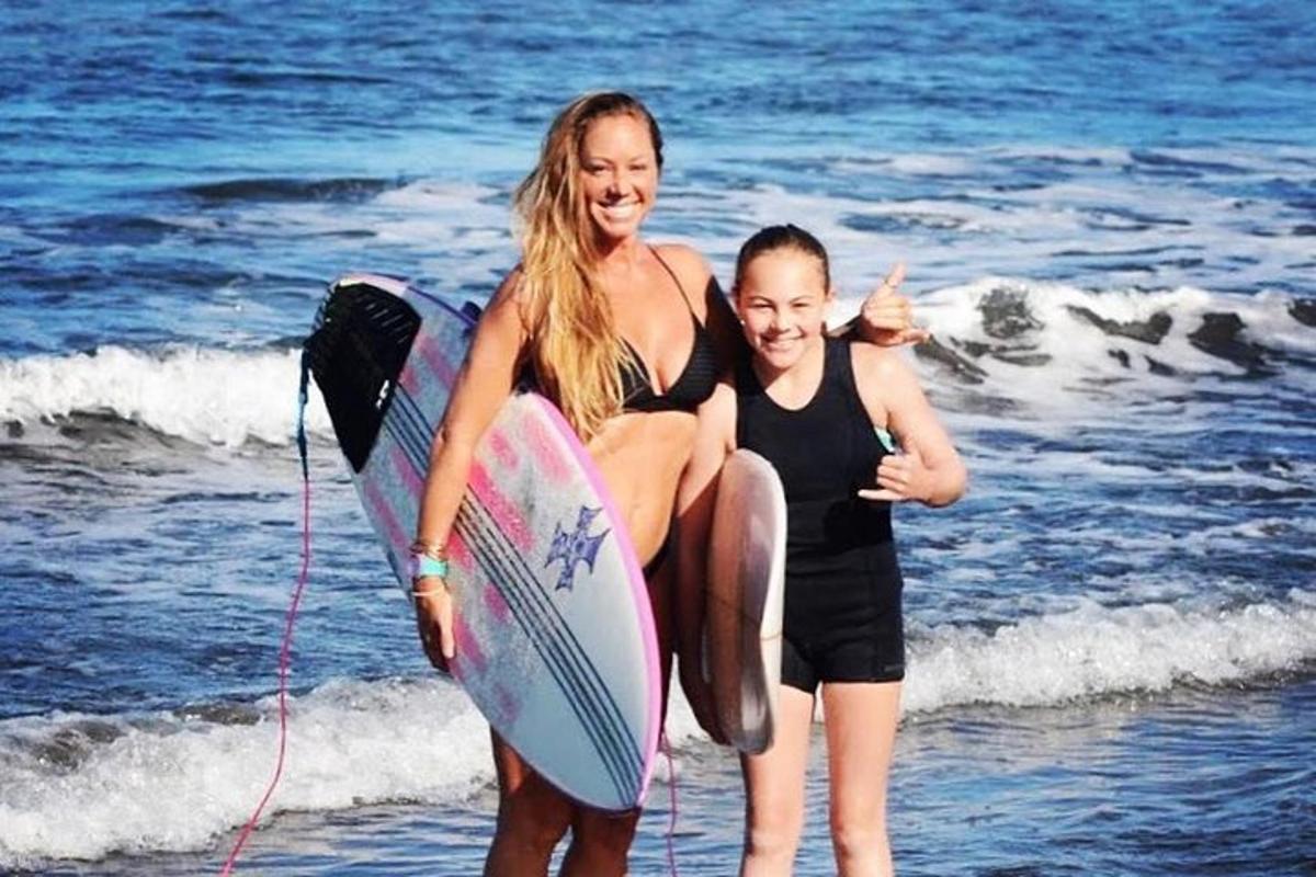 una donna e un bambino sulla spiaggia con una tavola da surf