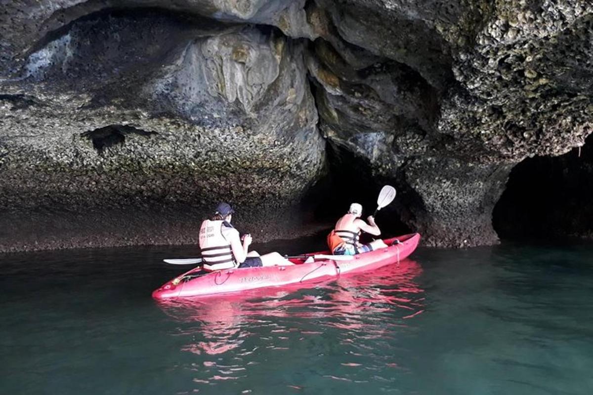 hai người trong một chiếc thuyền kayak màu đỏ trong một hang động