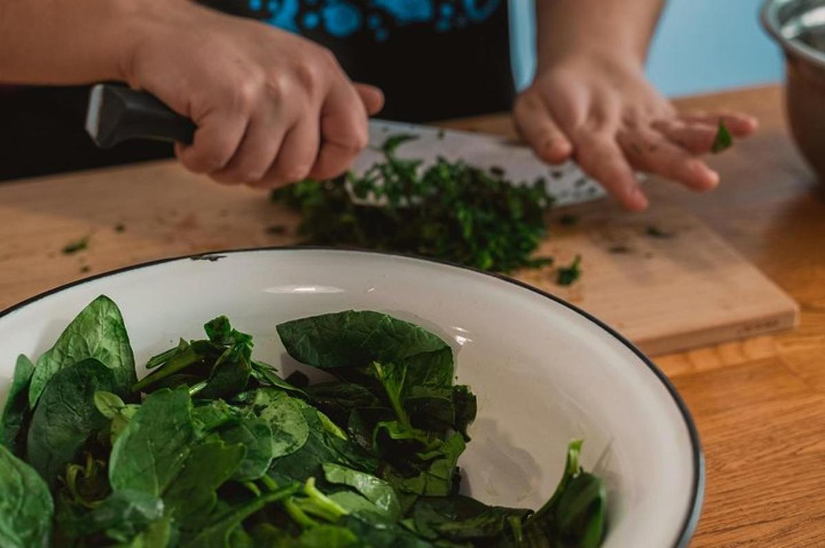 a person preparing a bowl of spinach on a cutting board