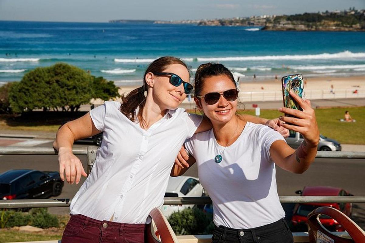 duas mulheres em pé perto da praia com um celular