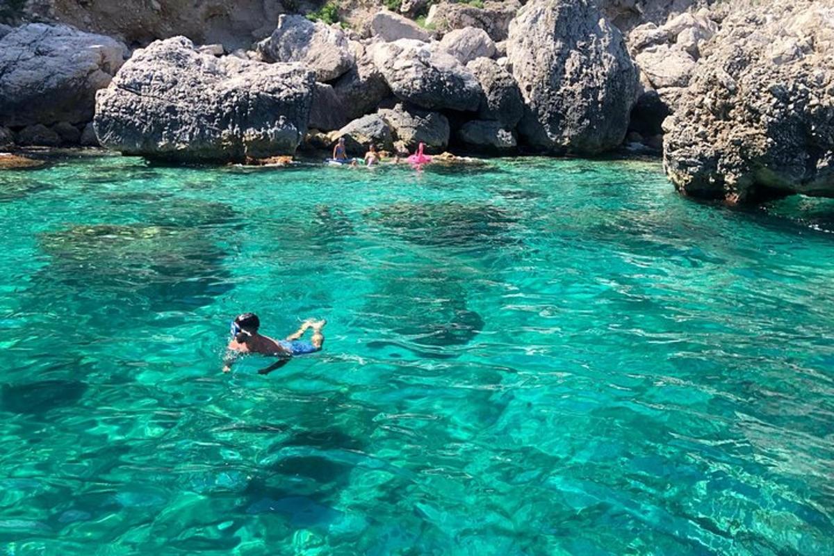 seseorang yang berenang di dalam air berhampiran beberapa batu