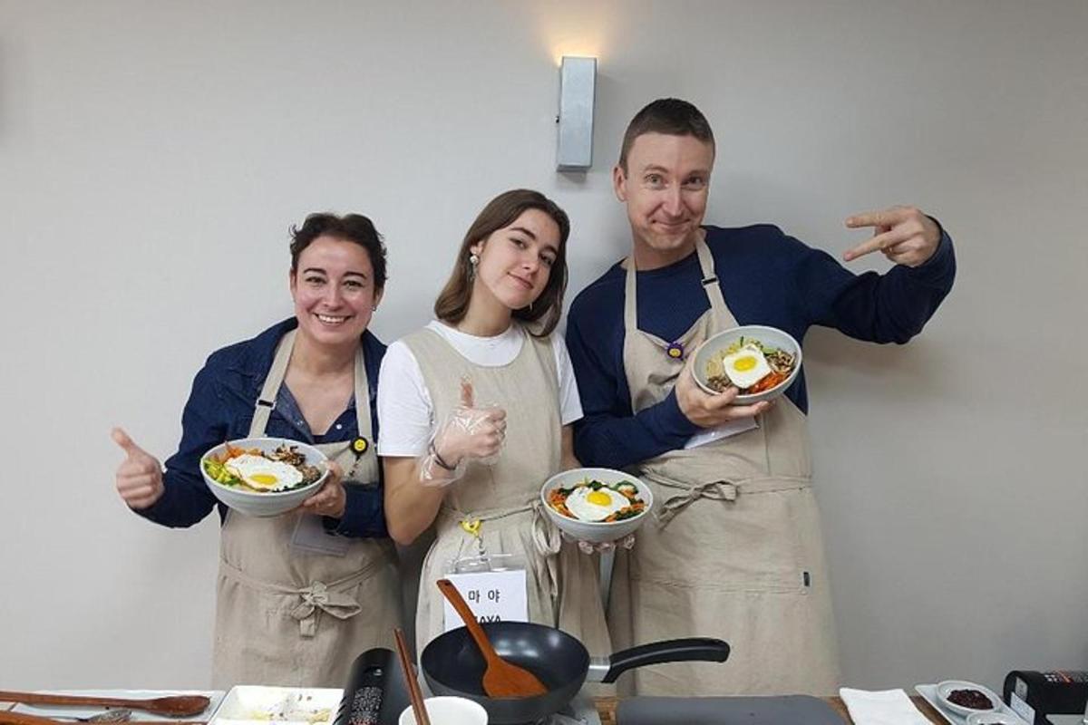 three people in a kitchen holding a bowl of food