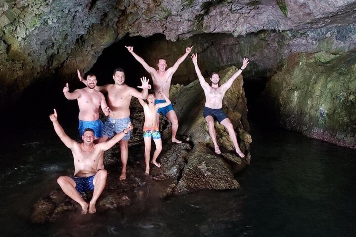 a group of men jumping into the water in a cave