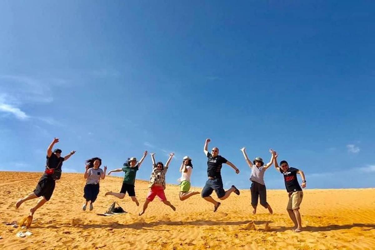en gruppe mennesker, der hopper i sandet på en strand