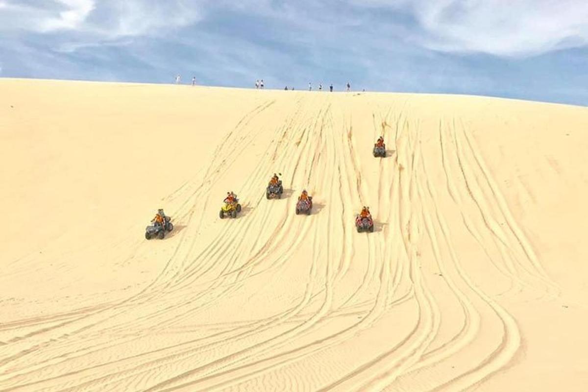 eine Gruppe von Menschen, die eine Sanddüne hinunterreiten