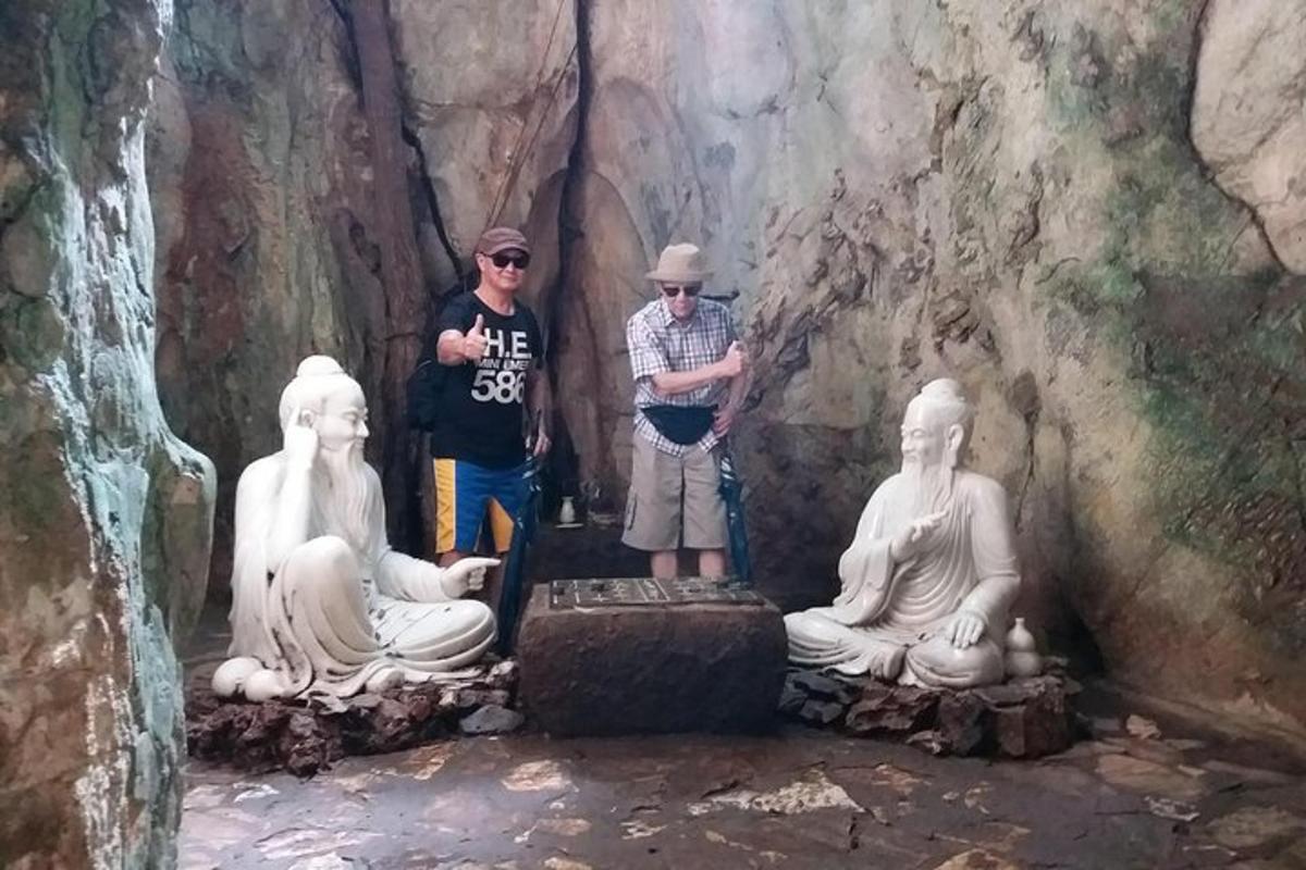 un gruppo di persone in piedi accanto alle statue in una grotta