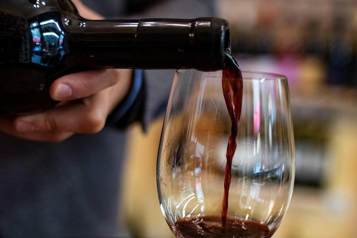a person pouring wine into a wine glass